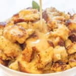 gravy being poured on a big bowl of bread dressing.