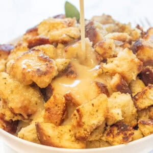 gravy being poured on a big bowl of bread dressing.