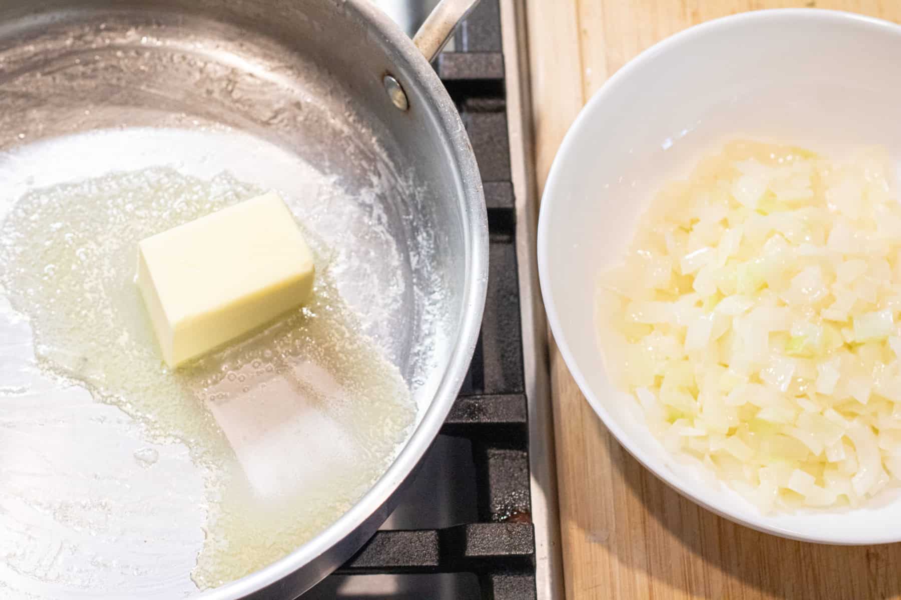 a picture of a pan with a stick of butter melting and a bowl of cooked onion next to it. 