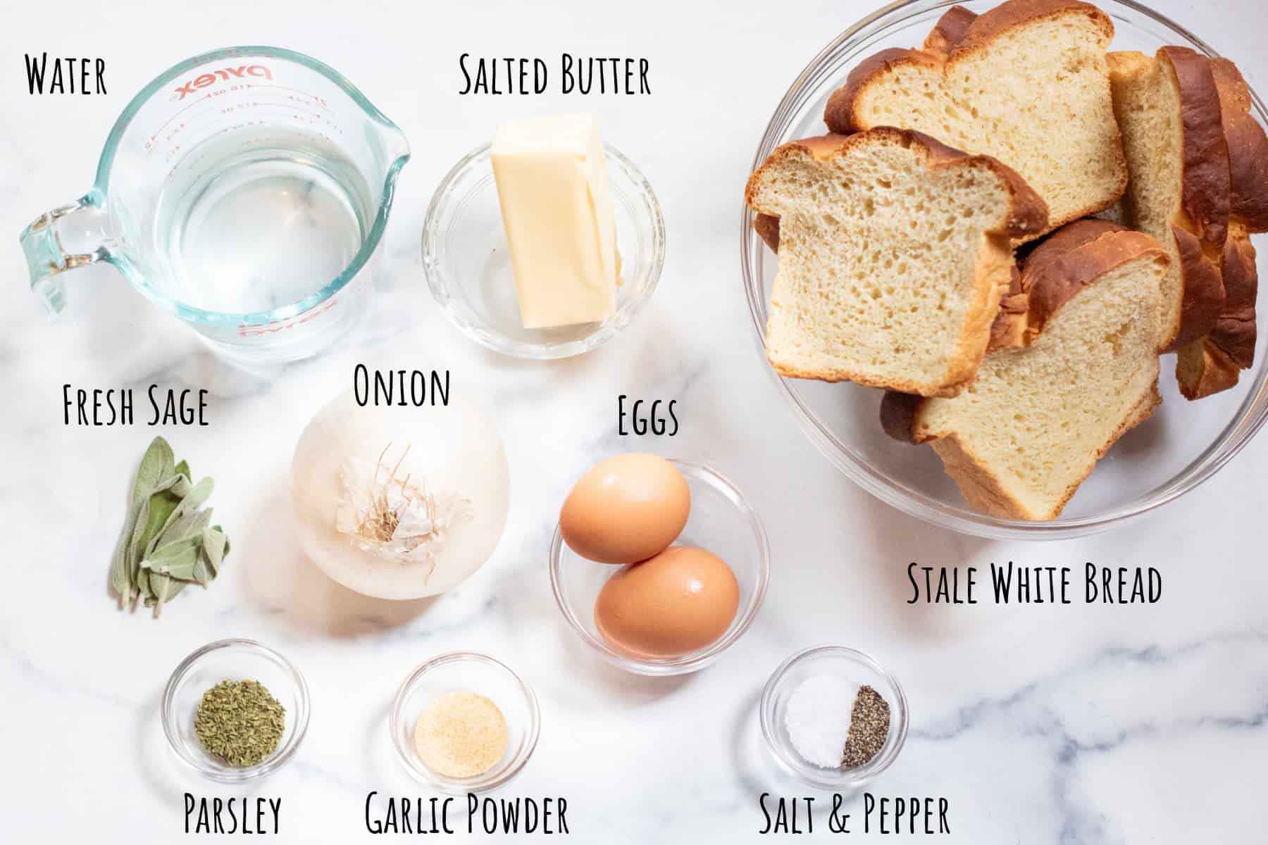 a bowl of bread, water, butter, eggs, fresh sage, salt and pepper, seasonings and garlic powder labeled. 