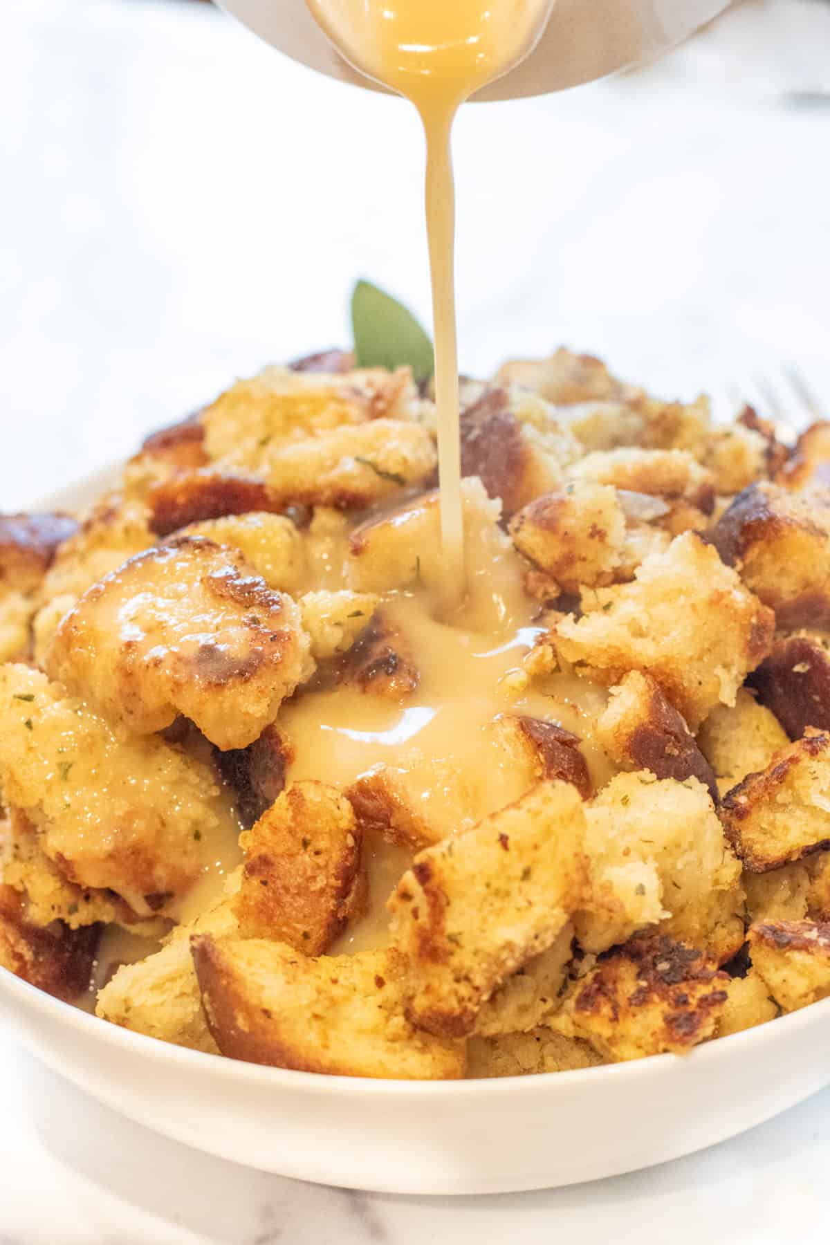 gravy being poured on a big bowl of bread dressing.
