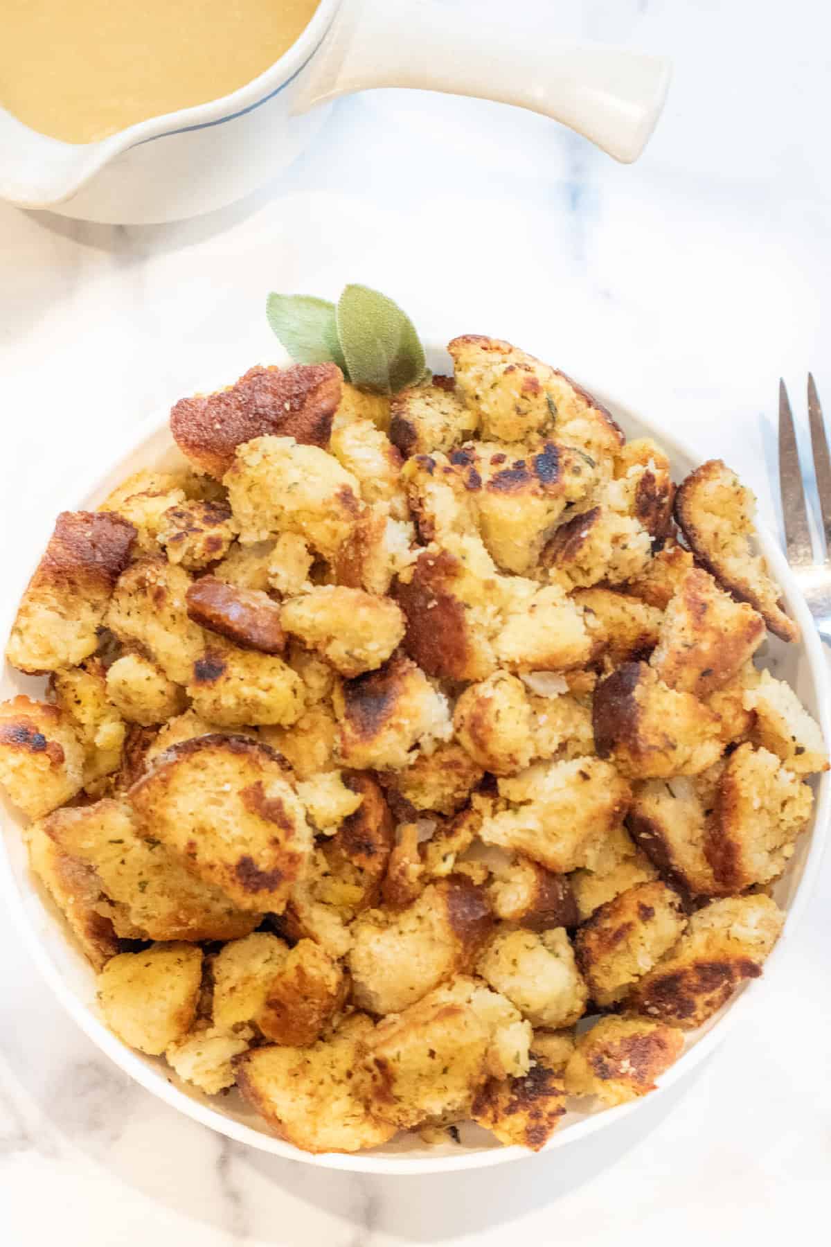 an overhead of a large bowl of bread dressing with some fresh sage.