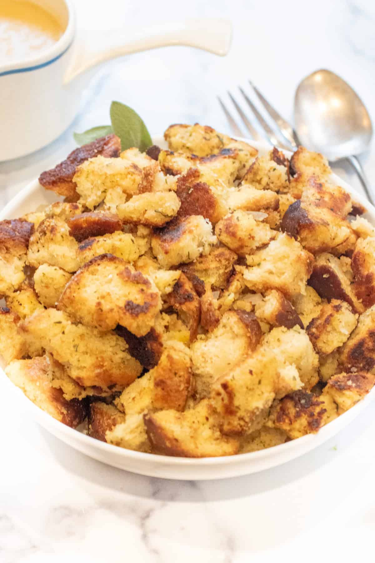 an overhead of a large bowl of bread dressing with some fresh sage.