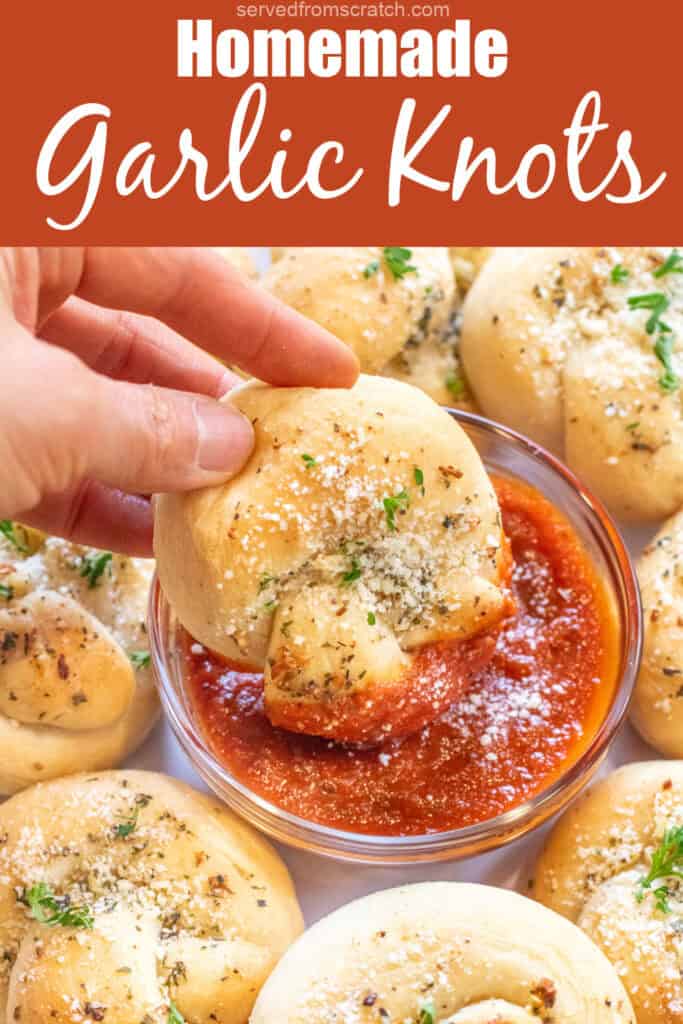 a hand dipping a garlic knot into a bowl of marinara sauce with Pinterest pin text.