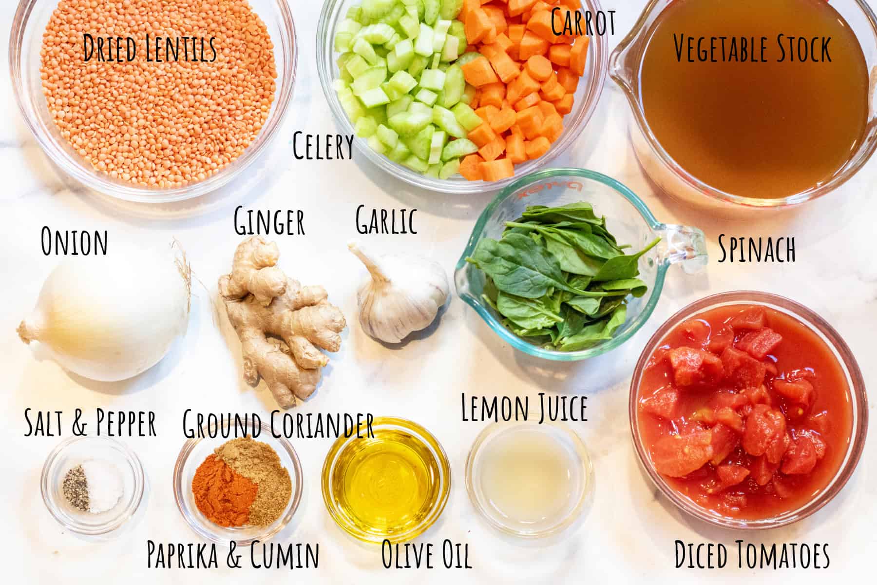 dried red lentils, stock, celery, carrots, onion, garlic, ginger, spinach, diced tomatoes, spices, olive oil and lemon juice labeled and in bowls. 
