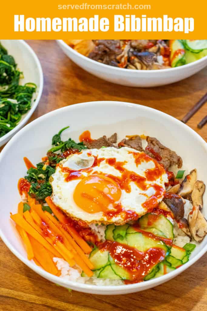 overhead of a big wide bowl of sliced carrots, cucumbers, spinach salad, beef, mushrooms, and an egg on top with sauce with Pinterest pin text.