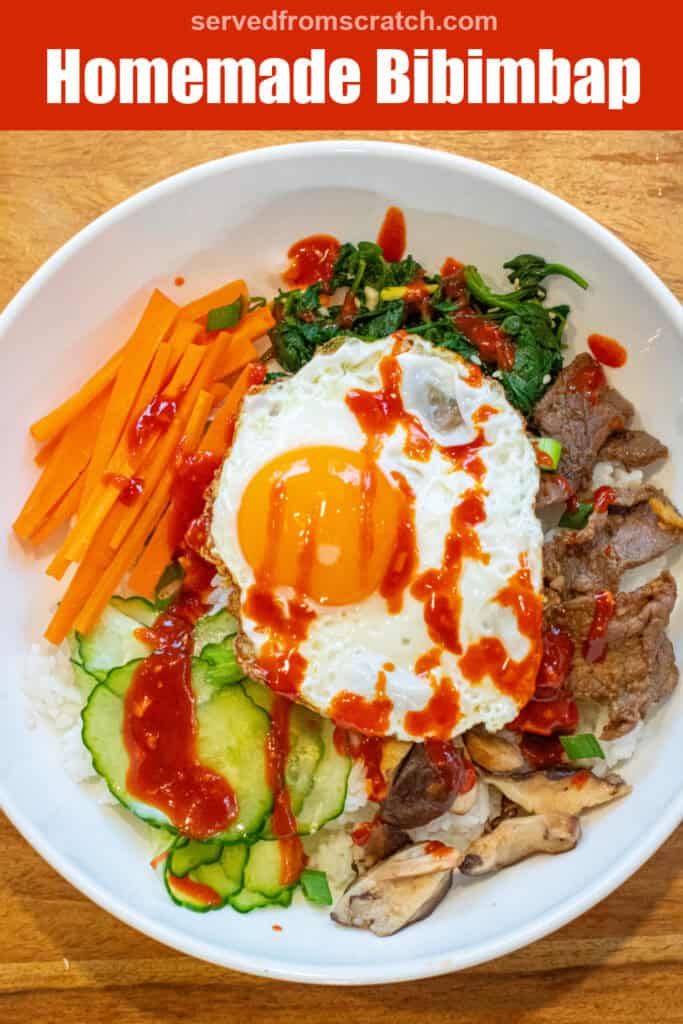 overhead of a big wide bowl of sliced carrots, cucumbers, spinach salad, beef, mushrooms, and an egg on top with sauce with Pinterest pin text.