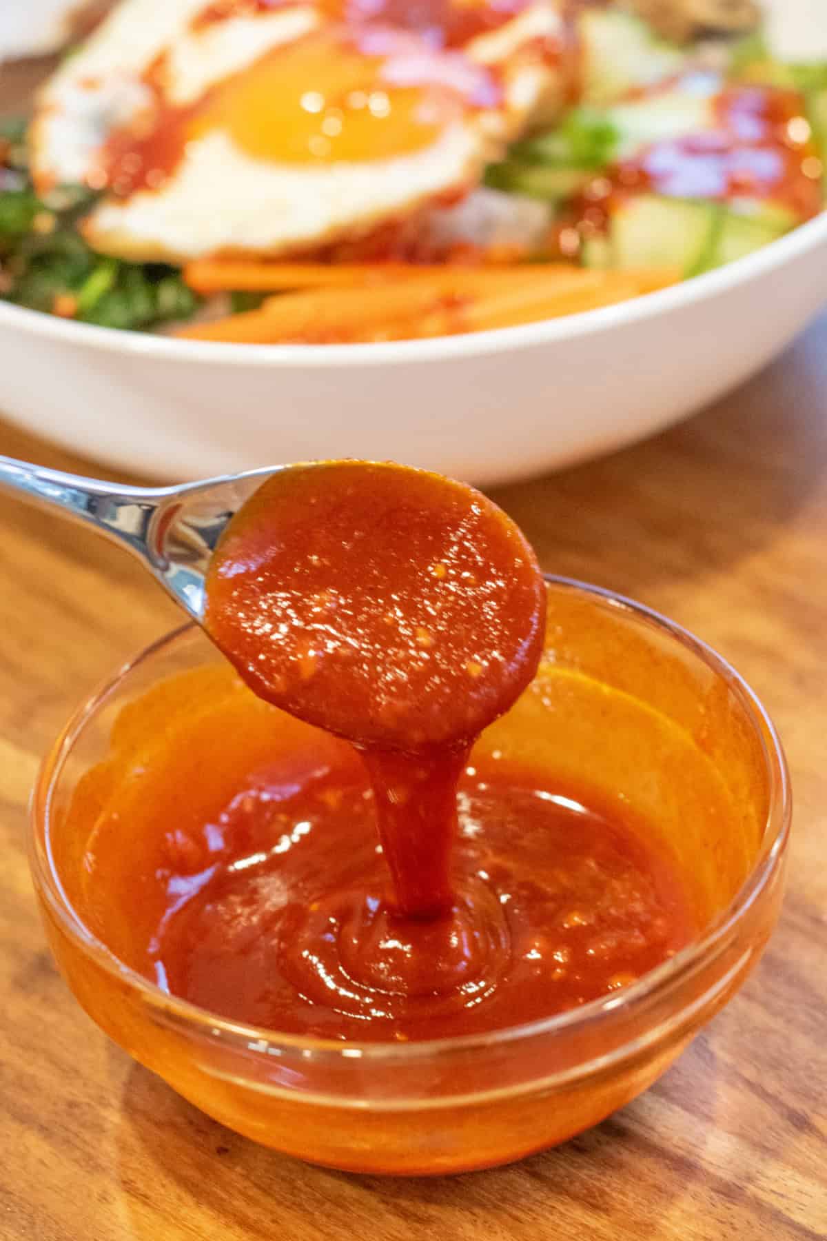 a bowl of bibimbap sauce with a spoon pulling some out.