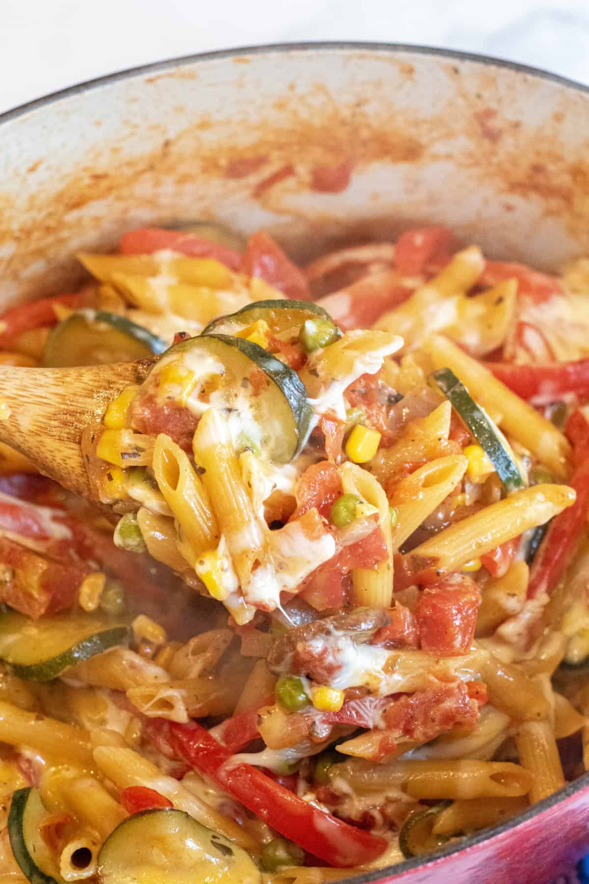 a pot of penne pasta with veggies and cheese. 