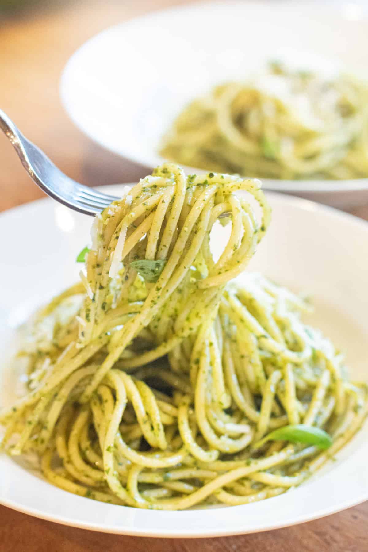 a bowl of pesto pasta with a fork holding some up.