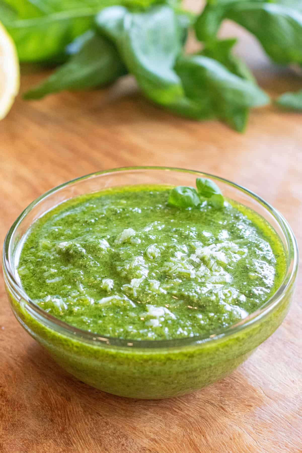 a bowl of pesto with a little parmesan cheese on top.