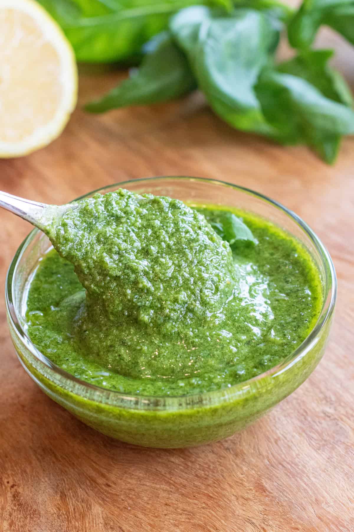 a bowl of pesto with a spoon in it.