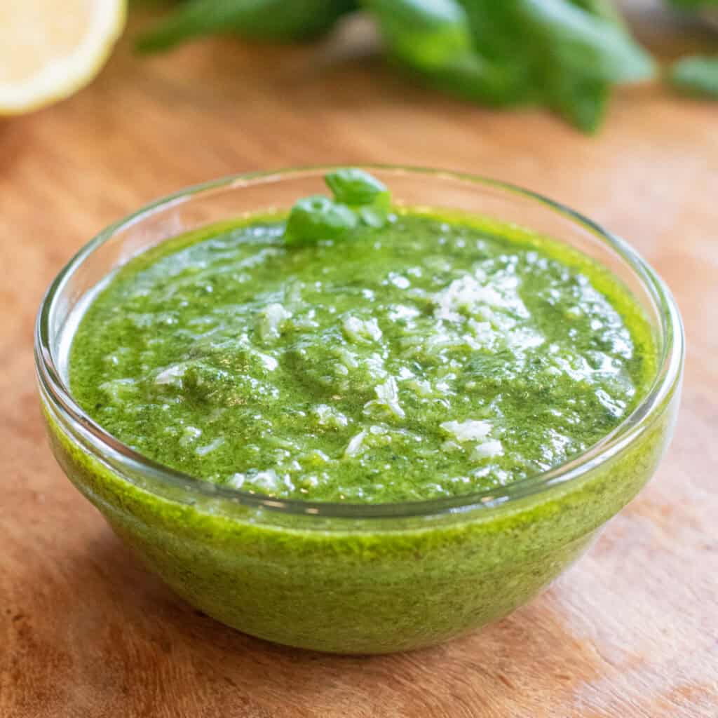a bowl of pesto with a little parmesan cheese on top.