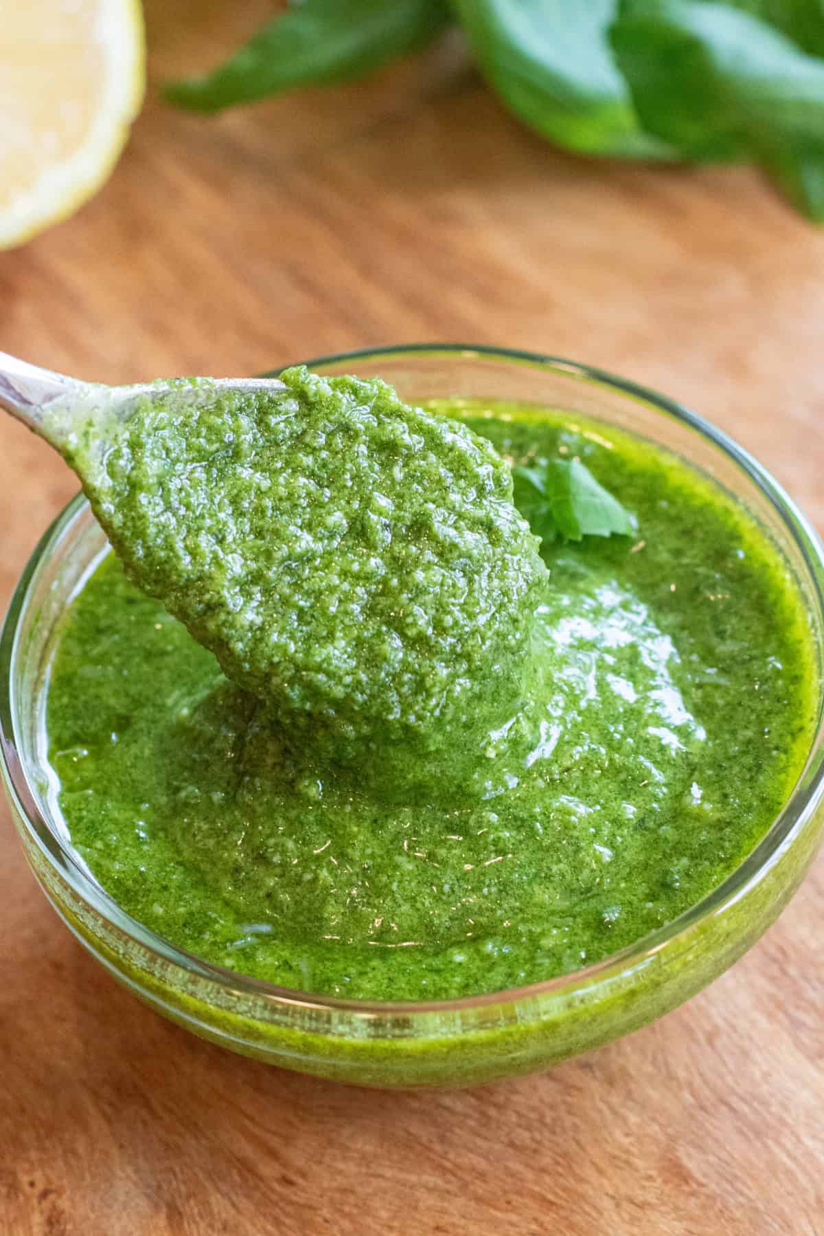 a bowl of pesto with a spoon in it.