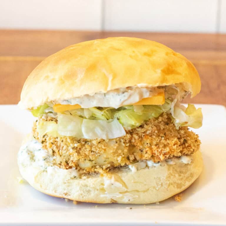 a breaded fish sandwich with lettuce and cheese on a brioche bun.