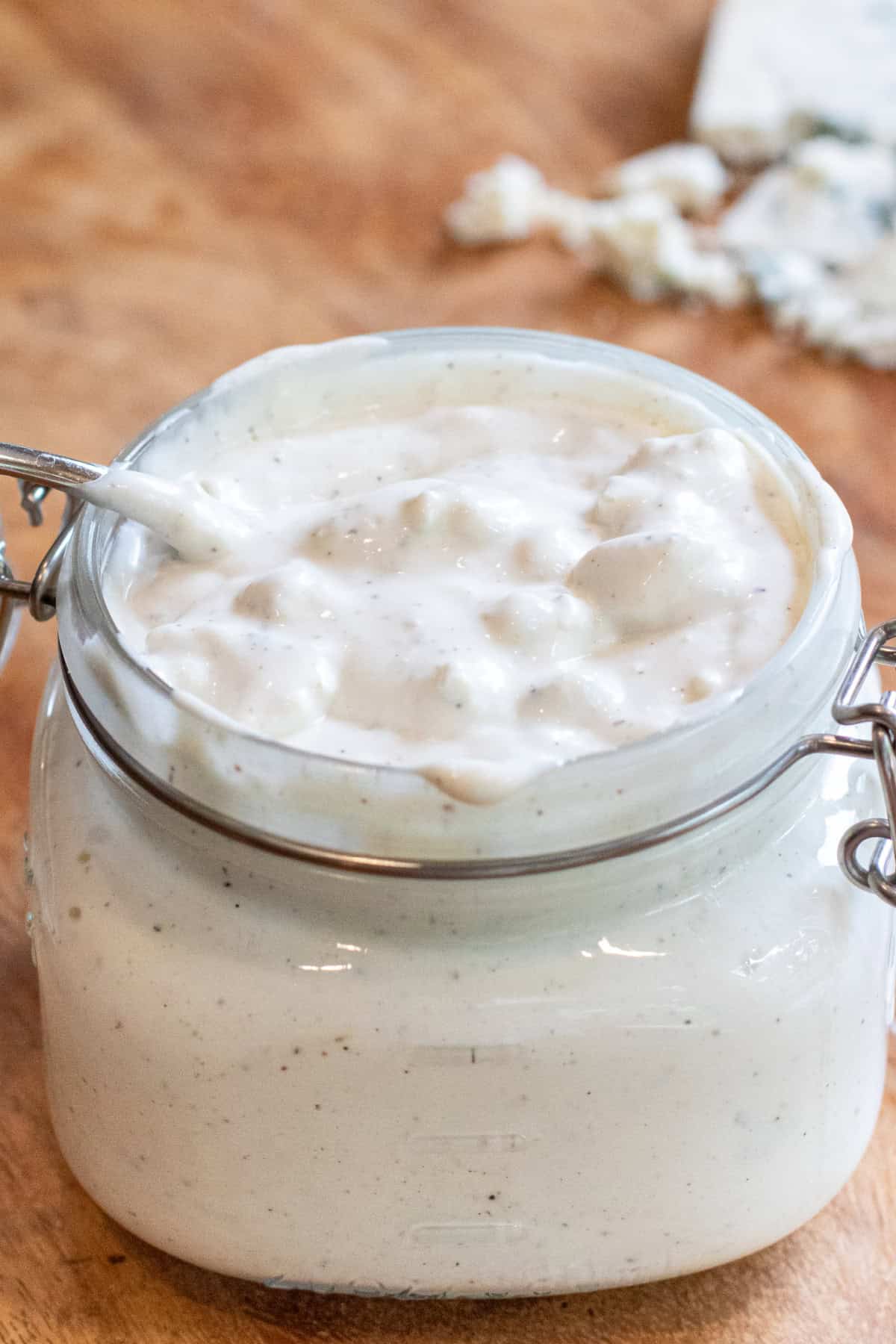 an open mason jar of blue cheese dressing with a spoon in it. 