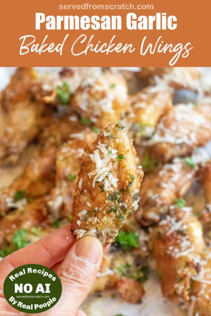 a hand holding a crispy chicken wing over a plate of chicken wings coated with Parmesan cheese with Pinterest pin text with NO AI sticker.