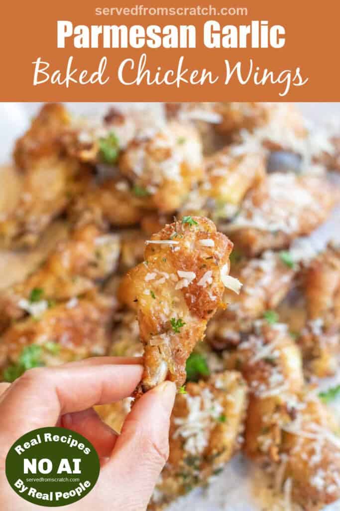 a hand holding a crispy chicken wing over a plate of chicken wings coated with Parmesan cheese with Pinterest pin text with NO AI sticker.
