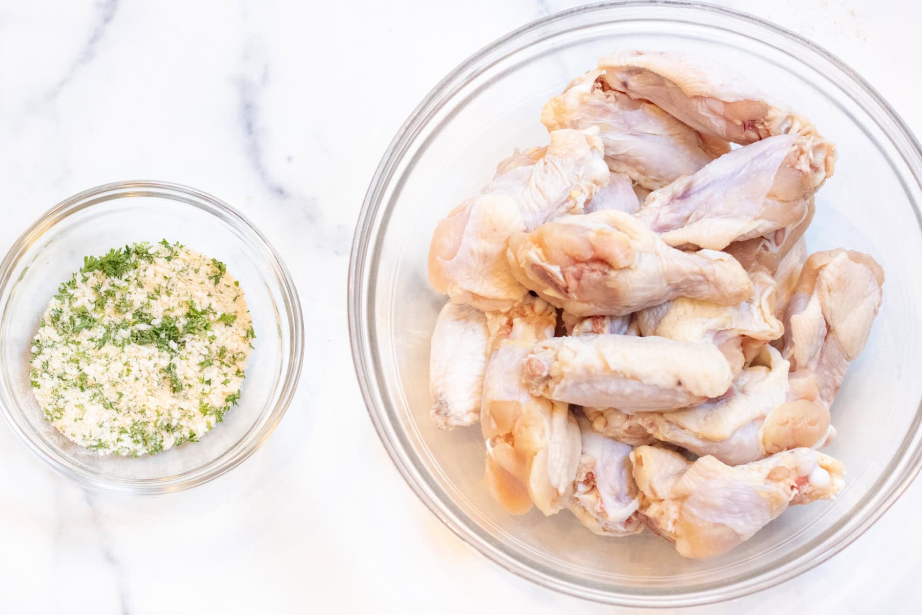 a bowl of mixed cheese, baking soda, a bowl of dried raw chicken wings.