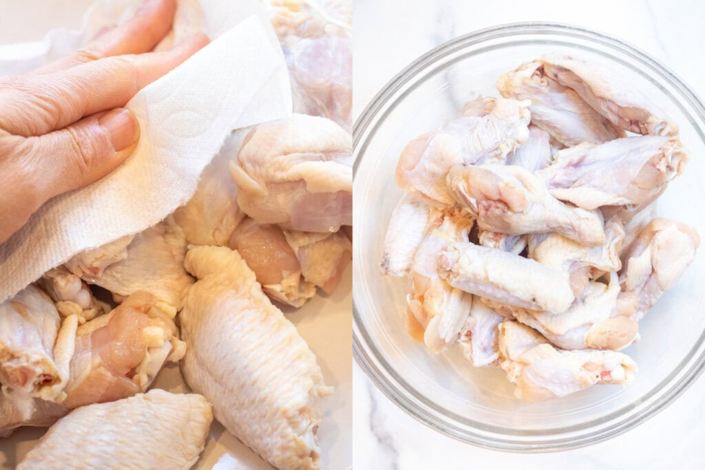 a hand with a paper towel drying raw chicken wings and them all in a bowl. 