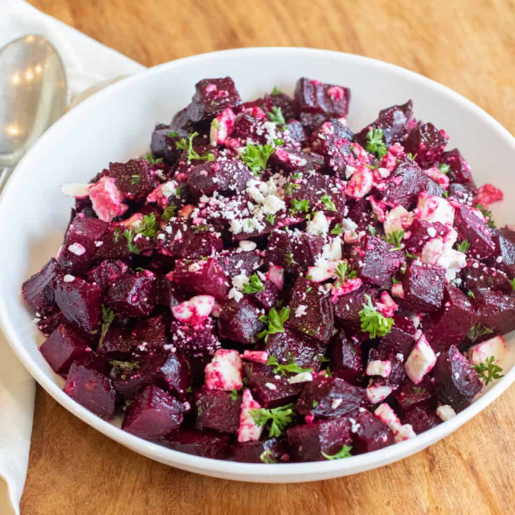 a bowl of cubed and roasted beets with feta and herbs.