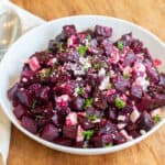 a bowl of cubed and roasted beets with feta and herbs.