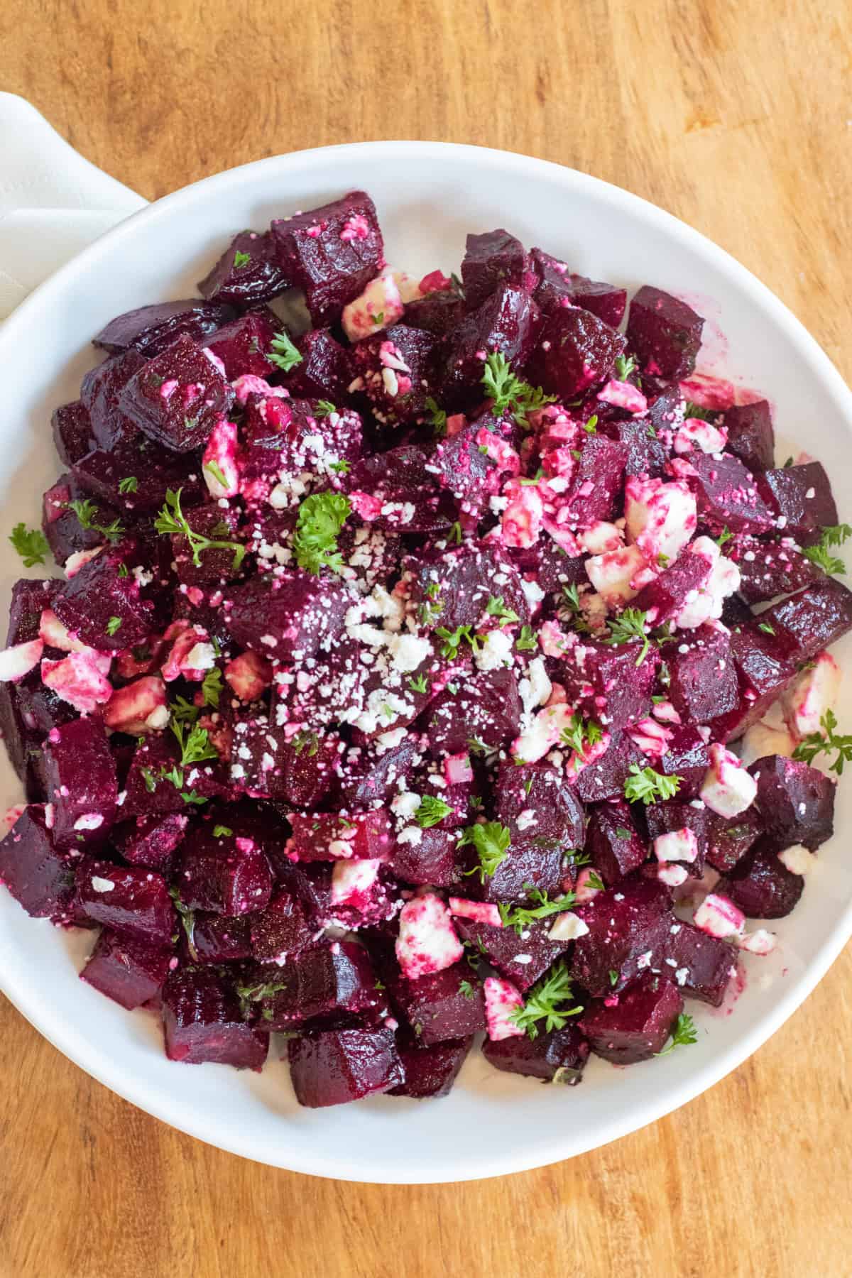 a bowl of cubed and roasted beets with feta and herbs.