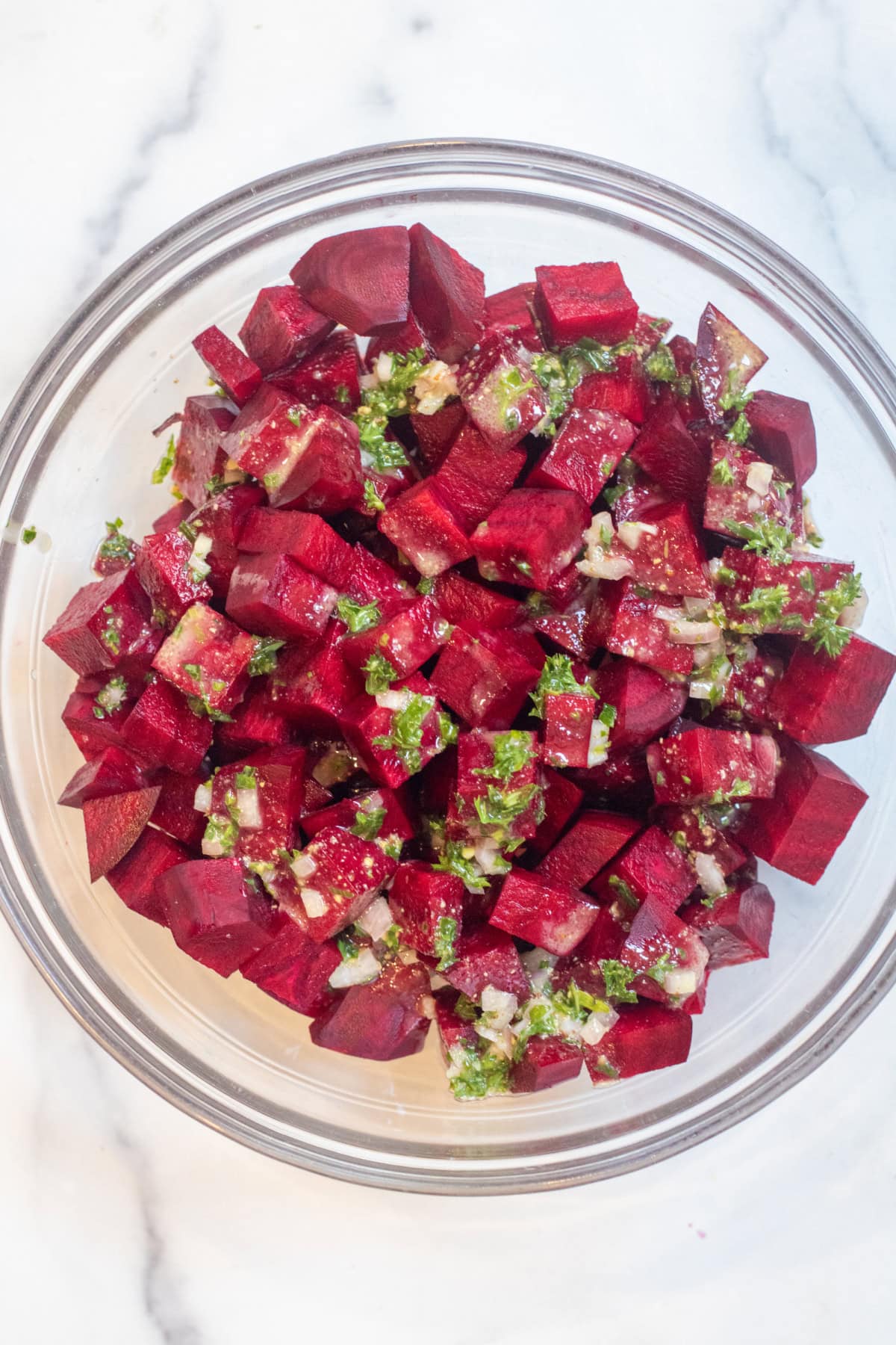 an overhead of a bowl of raw cubed beets and some vinaigrette poured on.