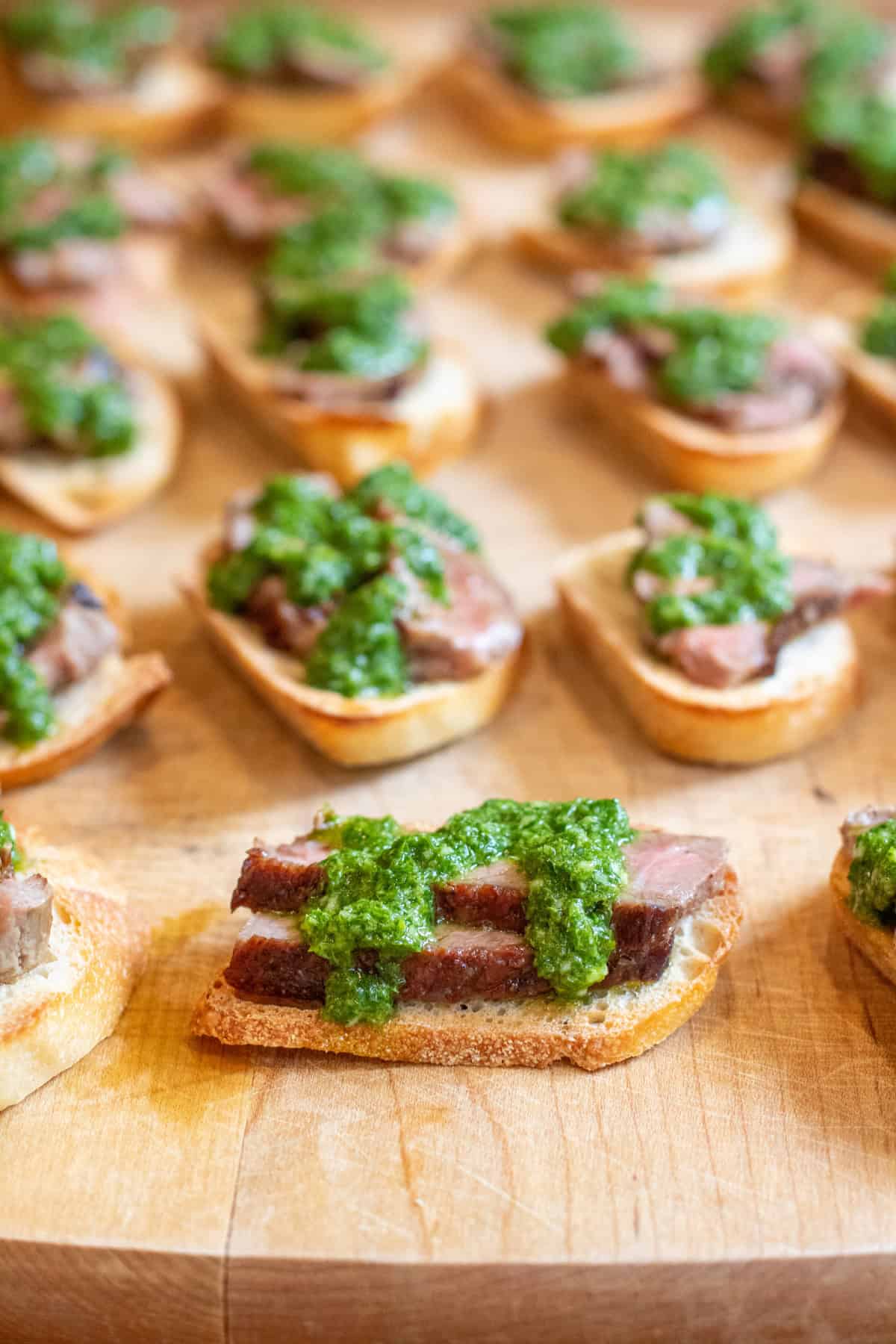 steak crostinis with chimichurri on top.