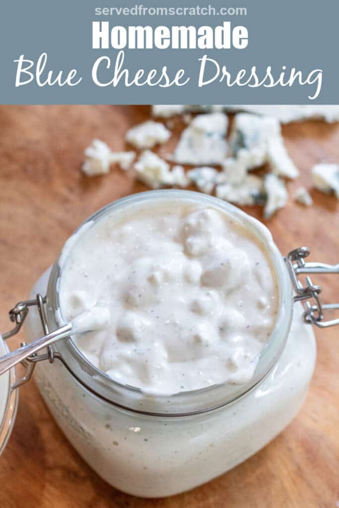 an overhead of an open mason jar of creamy chunky blue cheese dressing with a spoon in it with Pinterest pin text.