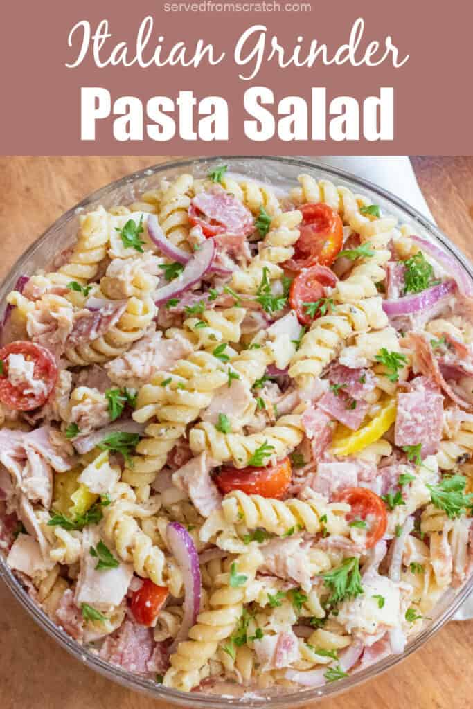 an overhead of a pasta salad with meats, cheese, tomatoes, parsley, and banana peppers with Pinterest pin text.