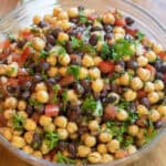 a salad with chickpeas black beans, tomatoes, and parsley.