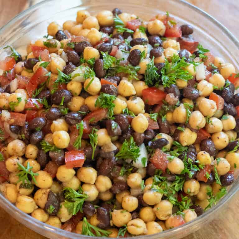 a salad with chickpeas black beans, tomatoes, and parsley.