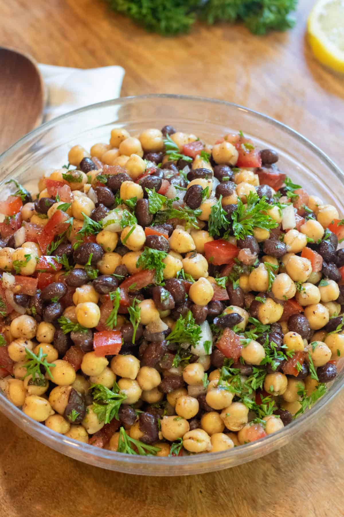 a salad with chickpeas black beans, tomatoes, and parsley.