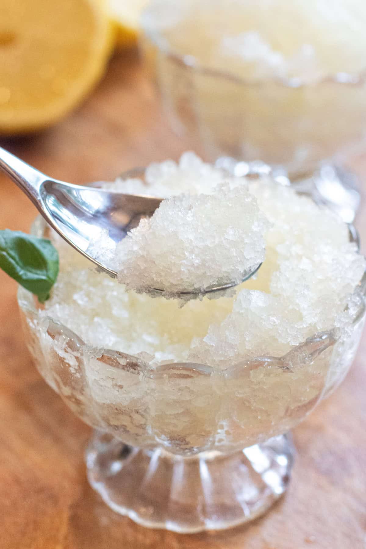 a small bowl of shaved ice with basil and a spoon.