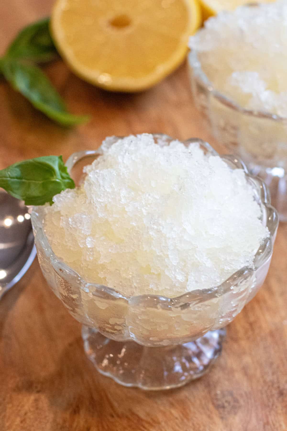 a small bowl of shaved ice with basil and a spoon.