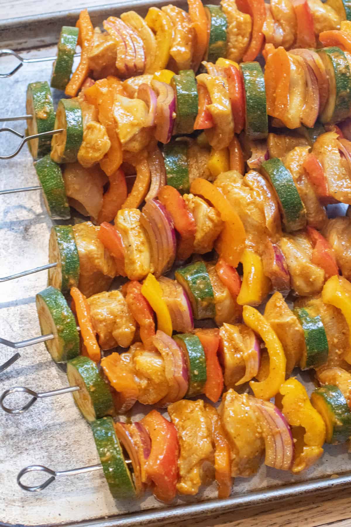 raw uncooked chicken, pepper, and zucchini skewers.