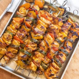 a tray of cooked chicken and pepper kebabs.