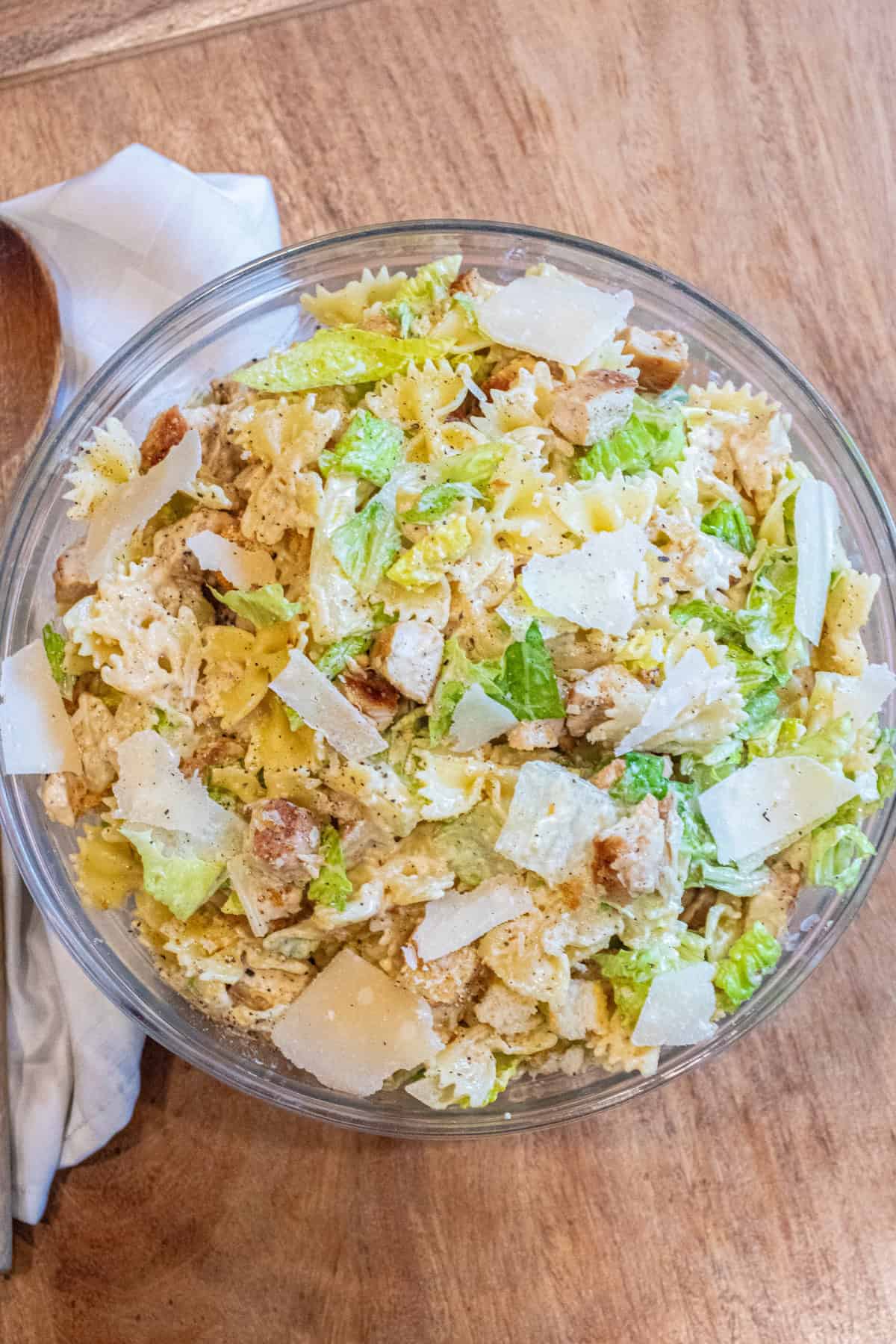 an overhead of a pasta salad with lettuce, chicken, croutons, and cheese.