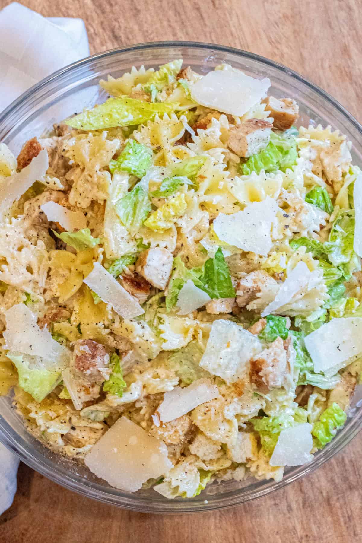 an overhead of a pasta salad with lettuce, chicken, croutons, and cheese.