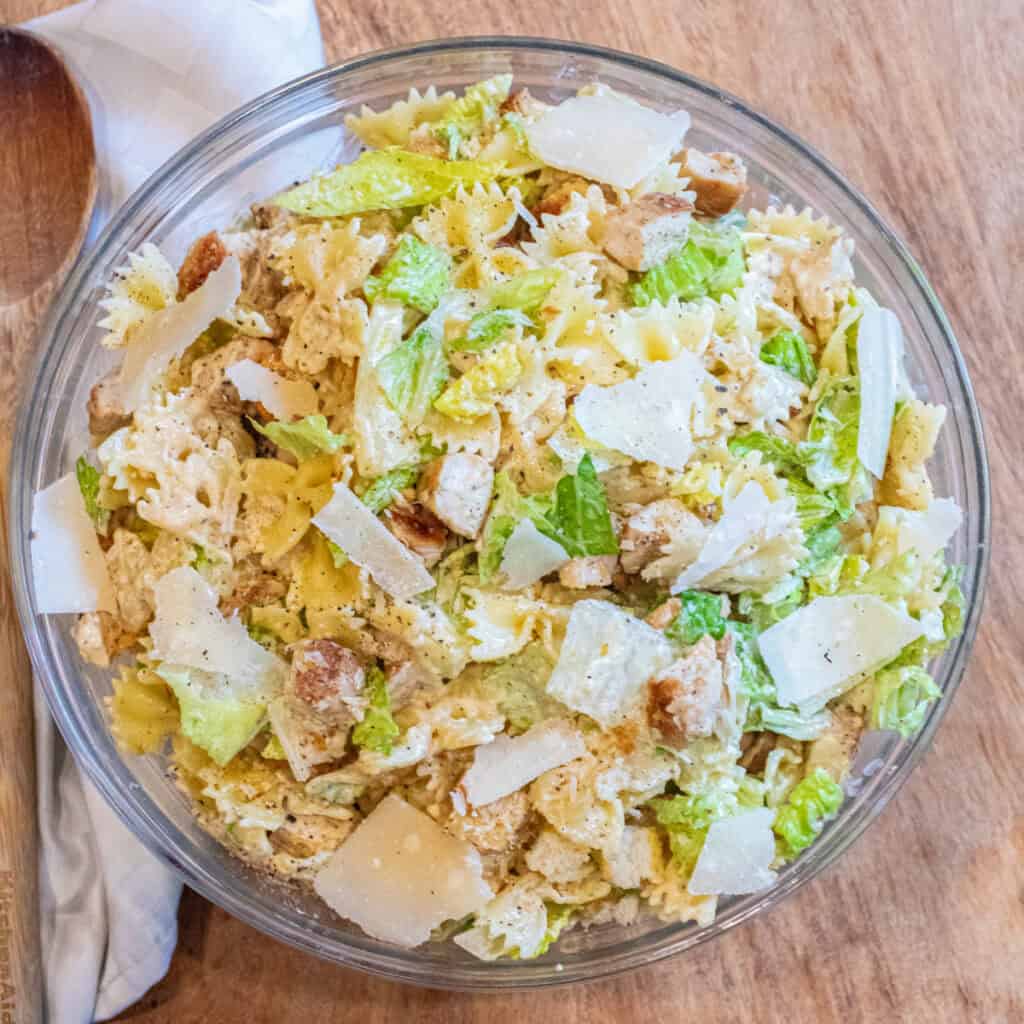 an overhead of a pasta salad with lettuce, chicken, croutons, and cheese.