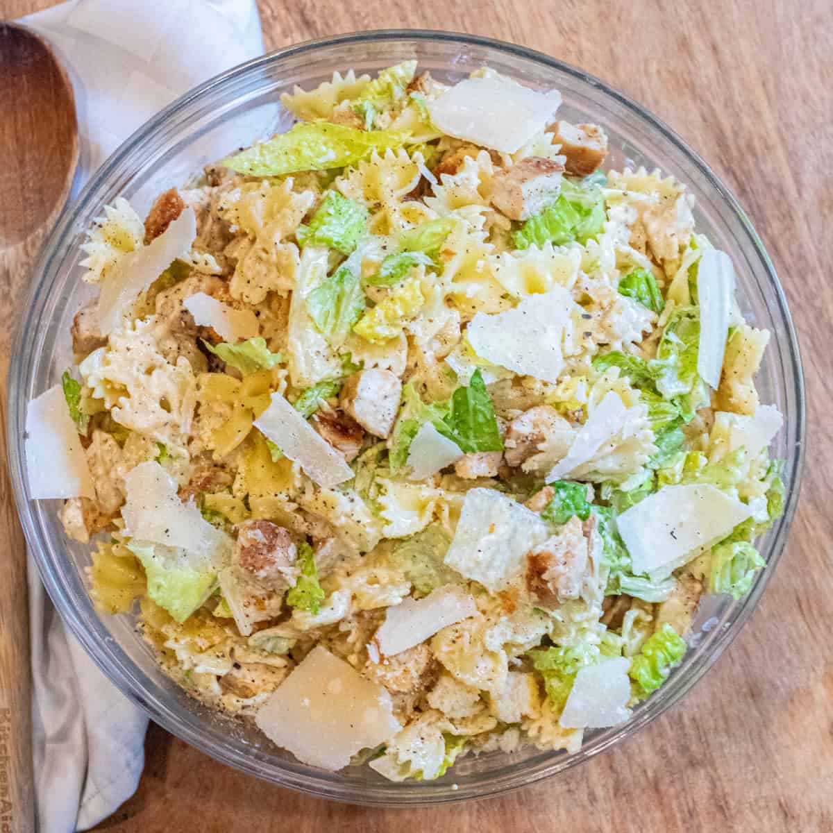 an overhead of a pasta salad with lettuce, chicken, croutons, and cheese.