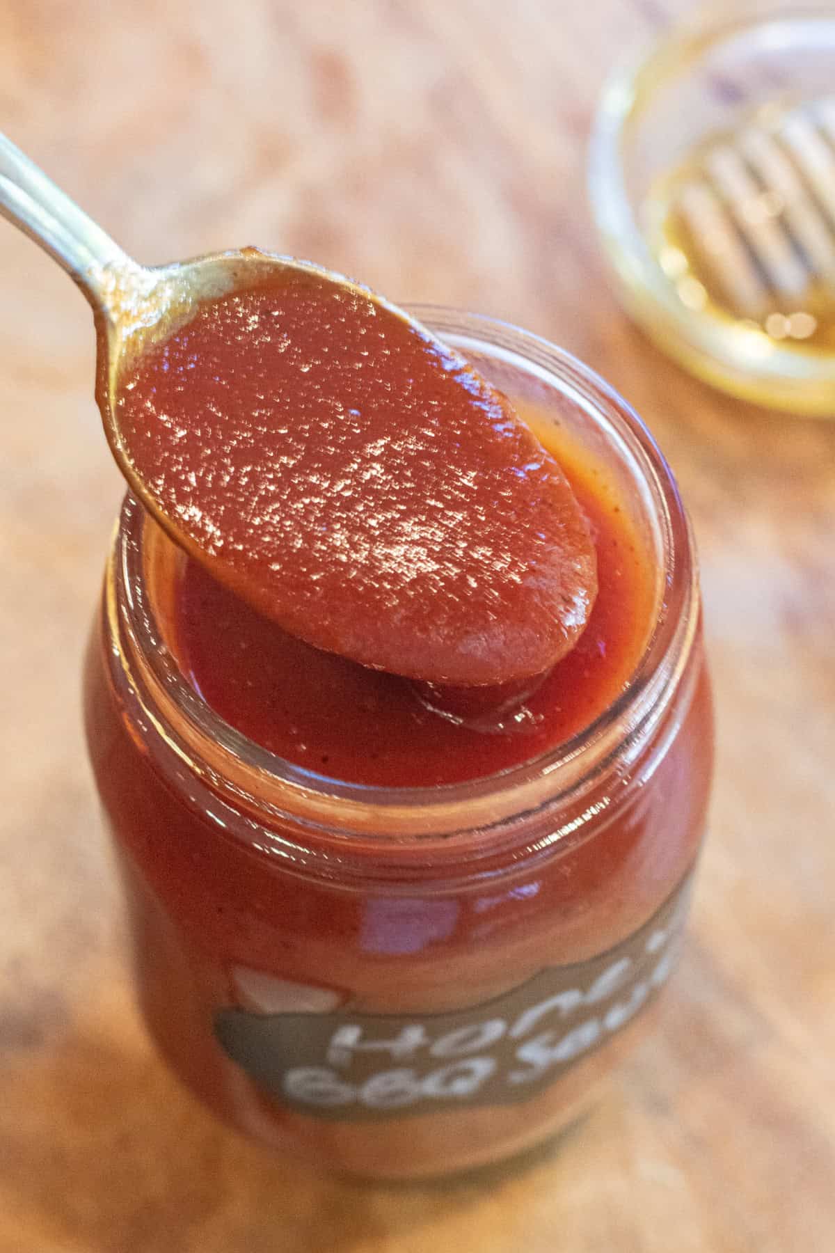an overhead of a open jar of BBQ sauce and a spoon of it.