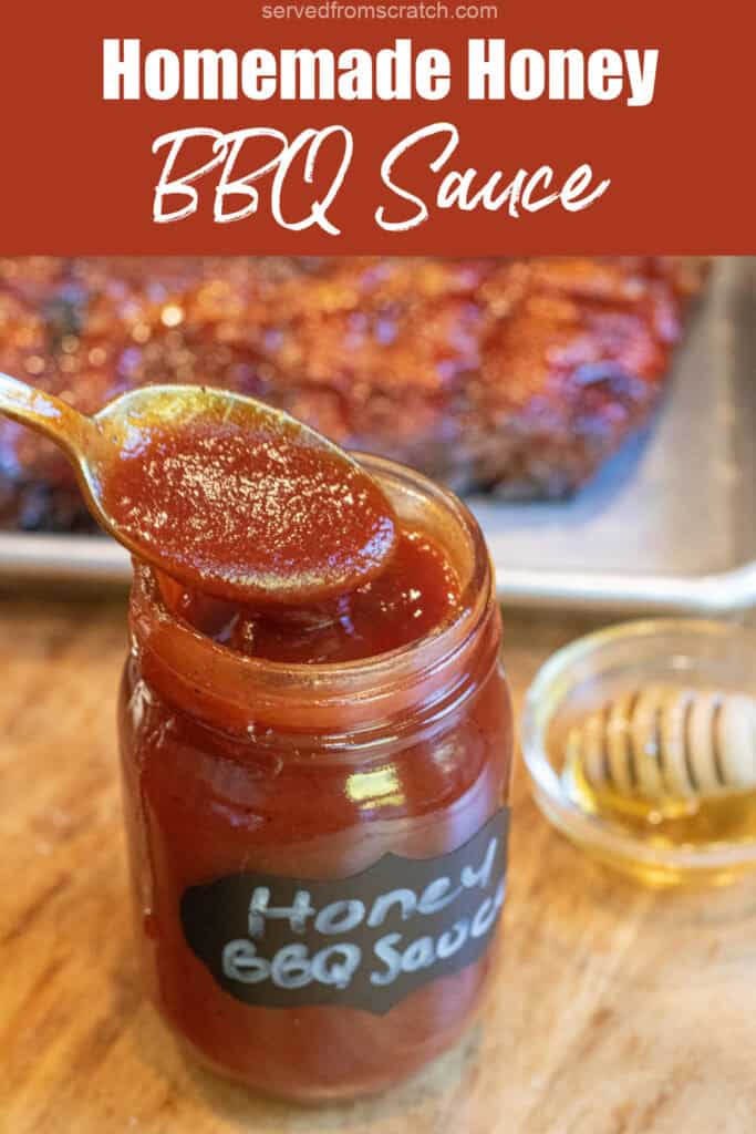 an open jar of honey bbq sauce with a spoon in front of a tray of ribs with Pinterest pin text.