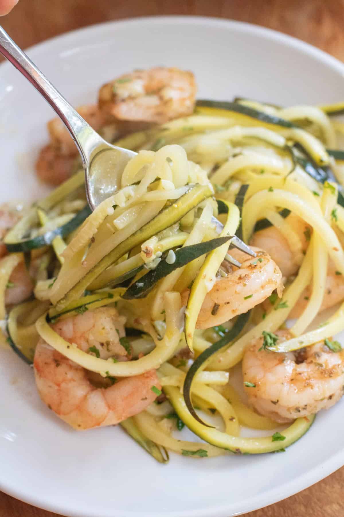 a plate of shrimp zoodle scampi with a fork full.