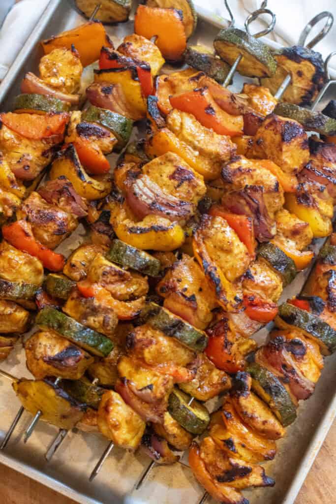 a tray of cooked chicken and pepper kebabs.