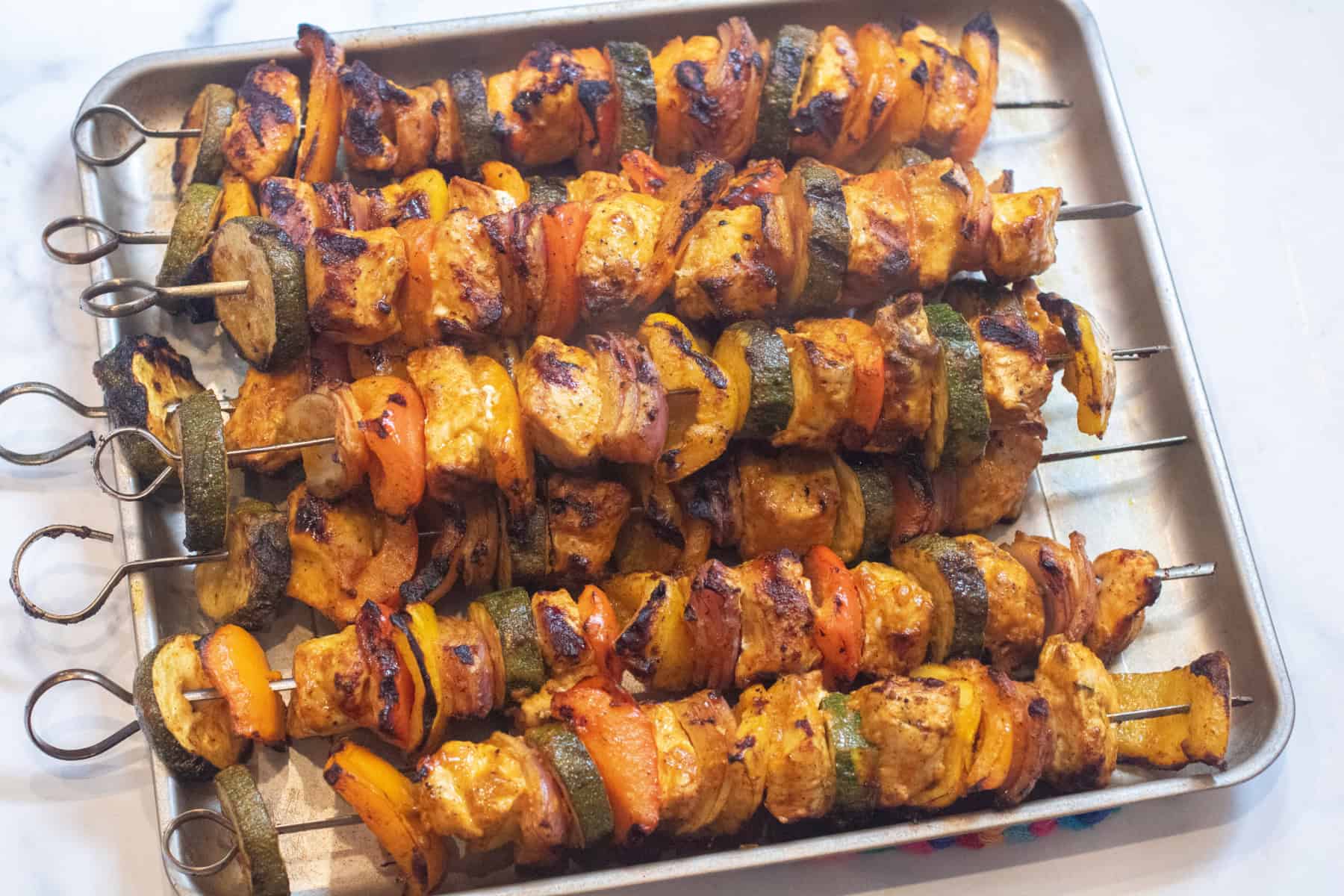 a tray of cooked chicken and pepper kebabs.