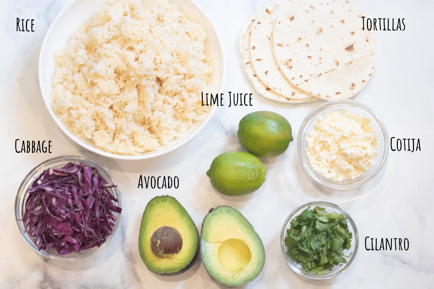 a bowl of rice, avocado, cilantro, cotija, tortillas, shredded cabbage, limes, labeled.