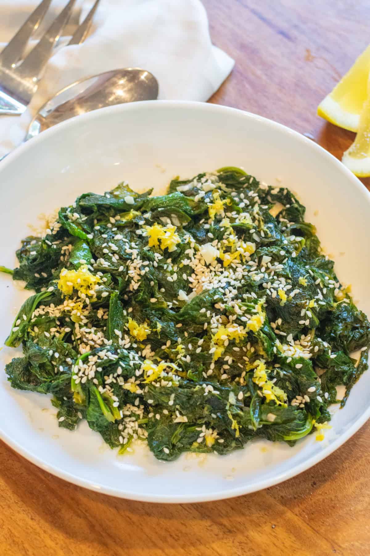 a bowl of cooked mustard greens with sesame seeds and lemon zest.