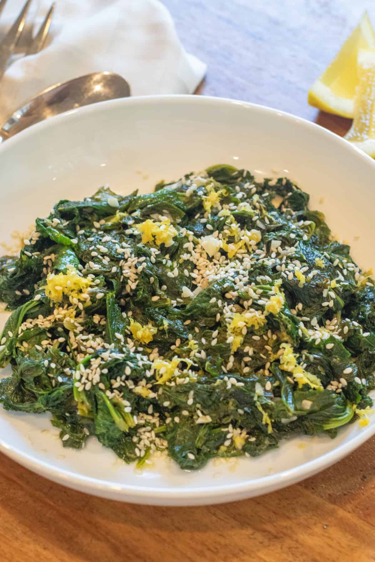 a bowl of cooked mustard greens with sesame seeds and lemon zest.